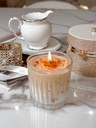 A lit Iced Caffè Candle on a beautiful marble dining table with Anaïs ribbon.