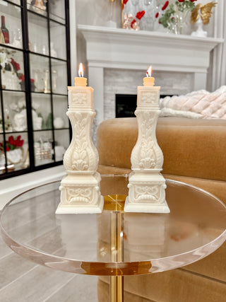  Stair Balusters Candle Set of 2 placed atop an acrylic table next to a plush couch.