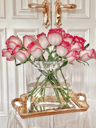 Olivia Glass Handbag Vase decorated with blooming florals in front of a luxurious door.