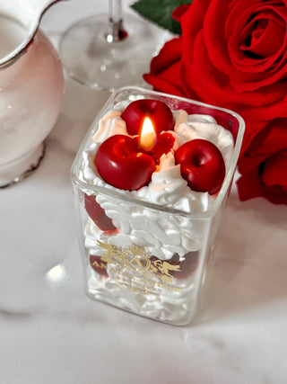 Cherry & Cream Delight Candle atop a marble table, next to a red floral bouquet.