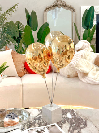 Golden Balloons Sculpture Decor atop a marble coffee table.