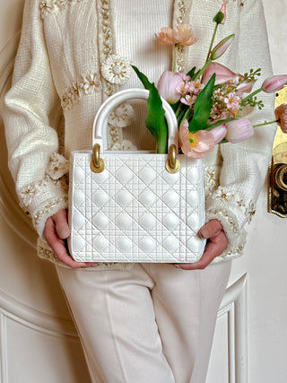 Woman gently holding the Scarlett Resin Handbag Vase in Beige with two hands.