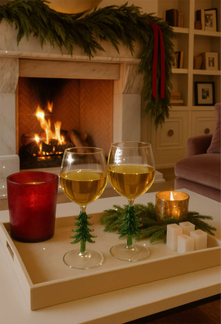 Merry Christmas Wine Flute Set of 2 with lit candles in front of a warm fireplace.