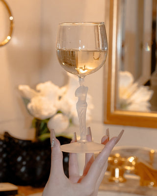 Hand holding a decorative wine glass with a blurred indoor setting.
