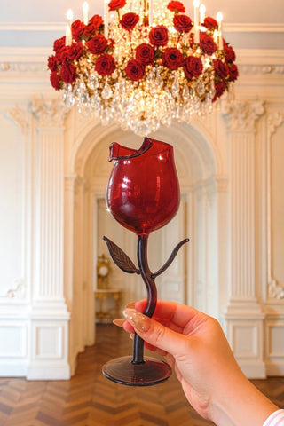 A woman holds a Rose For Rosé Glass Cup in front of a luxurious chandelier.