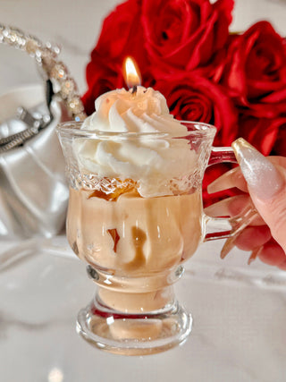 A lit Vanilla Ice Cream Latte Candle gently held by its handle.