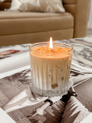 A lit Iced Caffè Candle atop a haute magazine.