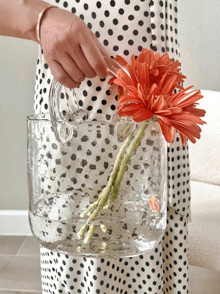 An Olivia Glass Handbag Vase decorated with orange flowers.