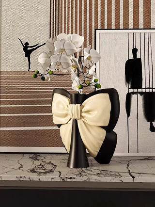 Elegant Bow Tie Vase With Artificial Orchid Flower in front of modern art.