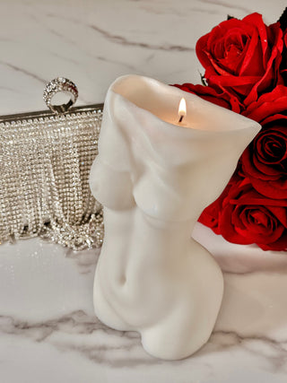 Anaïs Feminine Bust Candle atop a marble table next to a red floral bouquet.