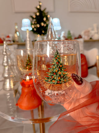 A Christmas Confetti Glass Cup delicately held to display its Christmas tree print.