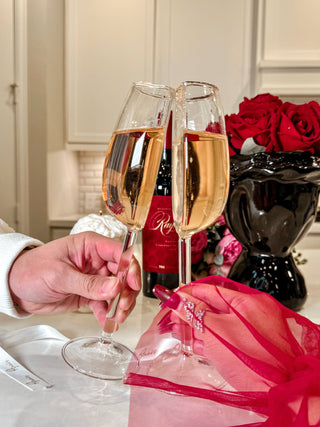 A couple toasting the 'We are One' Wine Glass Cup Set of 2 in a dining room.