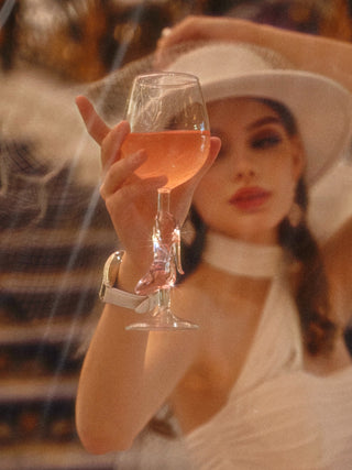 A woman enjoying her night, toasting a Cindarella’s Glass Slippers Wine Glass.