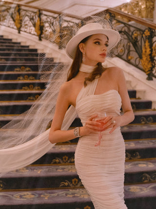 A woman gracefully walking down a grand stairway while holding a Cindarella’s Glass Slippers Wine Glass.