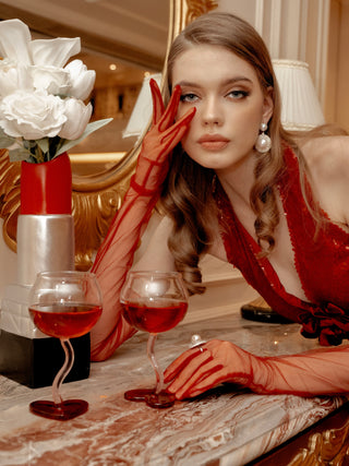 A woman in a red evening gown enjoying wine from a “My Valentine” Wine Glass Cup Set of 2.