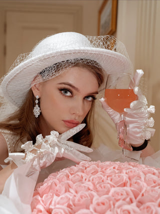 A woman with silk gloves holding a Cindarella’s Glass Slippers Wine Glass.