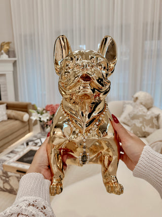 Golden French Bulldog Statue held up by woman.