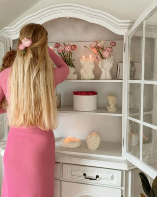 Woman admiring a collection of Anaïs Candle decor and candles.