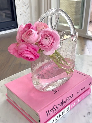 An Olivia Glass Handbag Vase decorated with lush pink flowers.