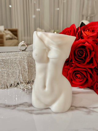 Anaïs Feminine Bust Candle atop a marble table with luxurious white curtains.