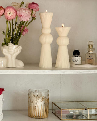 “Her” & Angelica Ceramic Vase Set of 2 with flower next to the Enzo Pillar Candle Set.