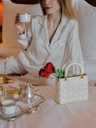 Scarlett Handbag Resin Vase on a hotel bed with flowers.