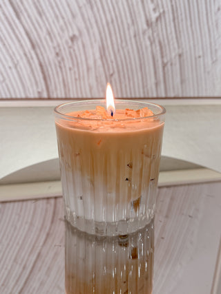 A lit Iced Caffè Candle on a reflective tray next to a modern framed print.