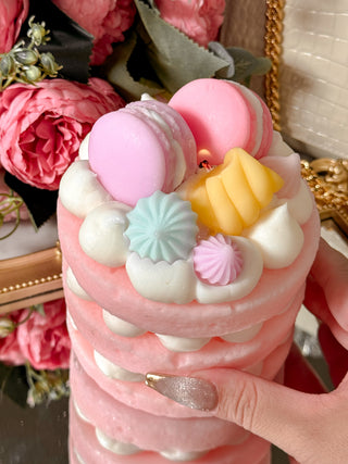 Dreamy Macarons & Cream Tart Candle held in hand with a floral bouquet in background.