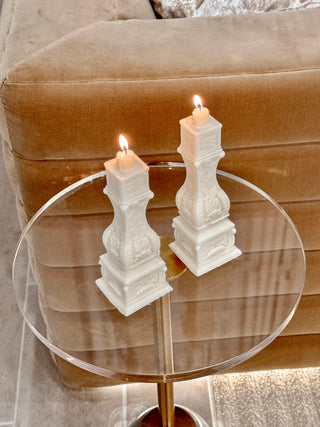 Stair Balusters Candle Set of 2 placed atop an acrylic table next to a plush couch and carpet.