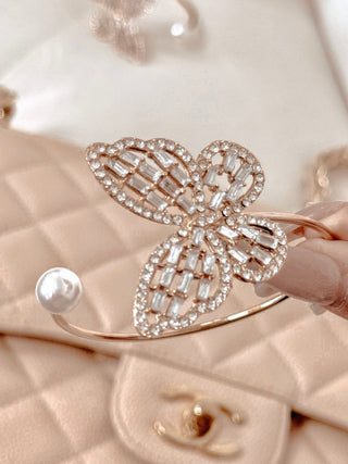 Dreamy Butterfly Bangle Bracelet with a blurred background of another bangle bracelet and a luxury handbag.