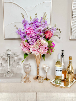 Faux Blooming Floral Arrangement atop a credenza with champagne flutes.