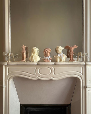 A Winged Victory Candle amongst other Anaïs candles atop a credenza.