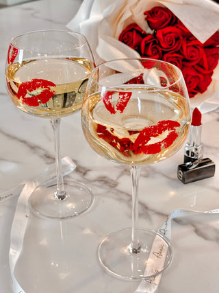 ‘Kiss Me, If You Adore Me’ Glass Cup Set next to a bouquet of roses.