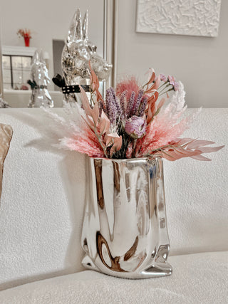 Luxe Bag Vase - Sliver Electroplated atop a luxurious cloth cloud couch.