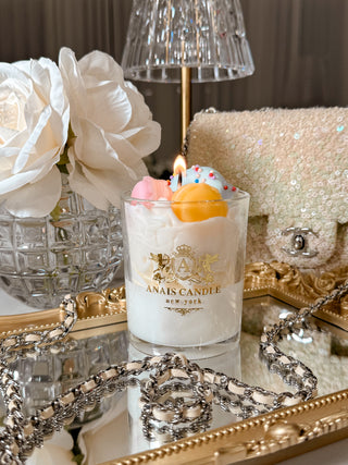 Macaron Parfait Candle surrounded by luxurious decor and flowers.