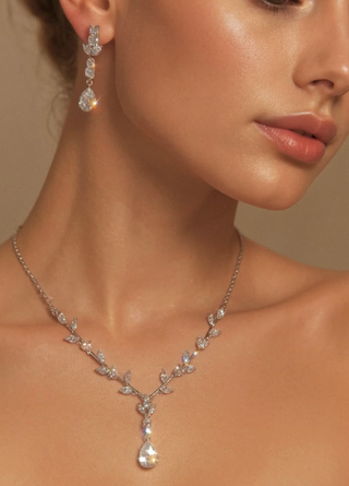 Close-up of a woman wearing a silver necklace and earrings with a neutral background