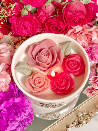 Monet's Garden Candle resting on top of a Grandeur Gold Mirror Tray surrounded by beautiful bloomed flowers.