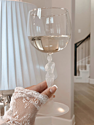 Venus Goddess Sculpture Wine Flute in front of a luxurious lampshade and spiral staircase.