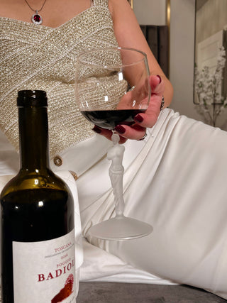 Model holding the Venus Goddess Sculpture Wine Flute posing with luxurious red wine in a master bedroom.