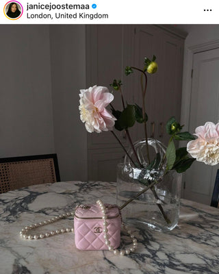 Olivia Glass Handbag Vase styled atop a marble dining table with large floral stemmed flowers by UK content creator Janice Joostema.