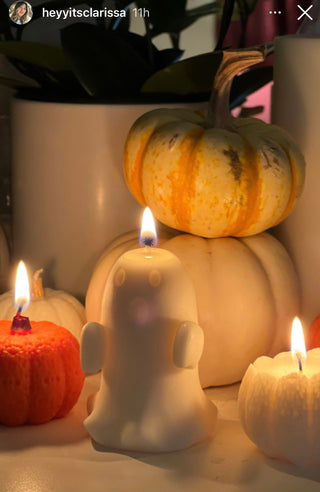 A Mini Ghost Candle next to a set of lit Anais pumpkin candles.