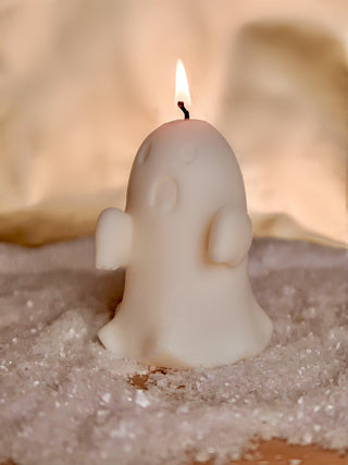 A lit Mini Ghost Candle on snowflakes.