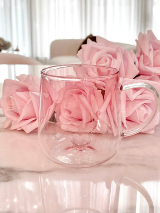 Heart You Glass Cup on a marble dining table surrounded by bloomed pink roses.