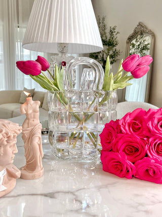 Camélia Padded Glass Handbag Vase in Rainbow with pink florals, in front of a crystal lamp.