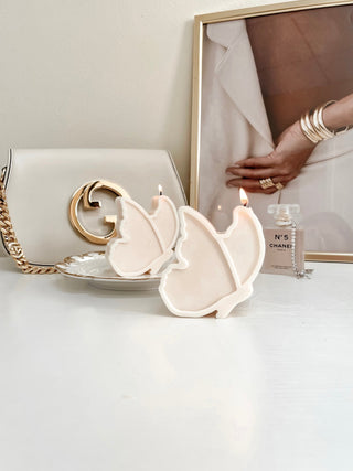 Two Dreamy Butterfly Candles with perfume and luxury handbag in the background.