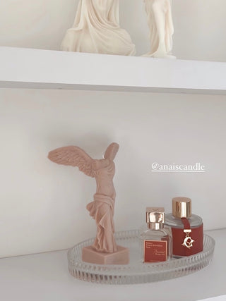 A Winged Victory Candle placed on a luxurious white shelf.