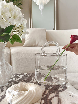 Olivia Glass Handbag Vase atop a luxury marble coffee table and a 3-Wick Halo Candle.